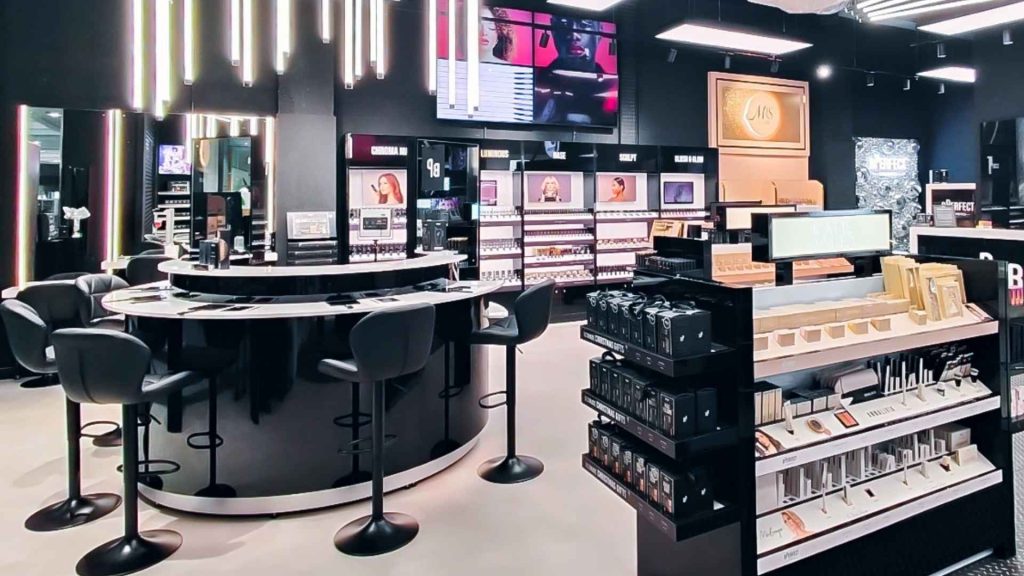 BPerfect Base Bar interior featuring sleek black counters, illuminated shelving displaying beauty products, and digital screens creating a vibrant and modern shopping environment