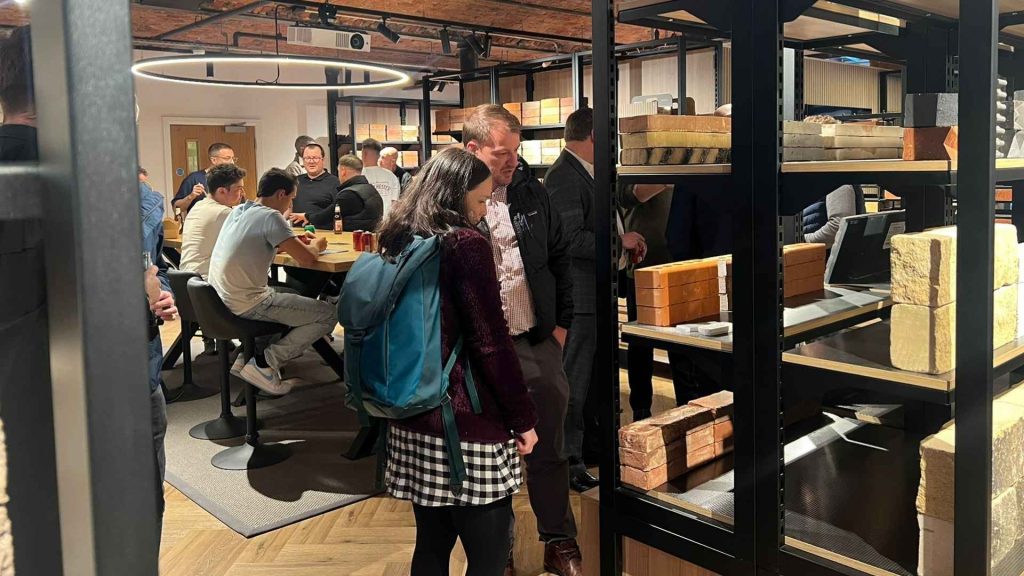 Manchester Brick Specialists showroom event with customers exploring premium brick samples on shelves and engaging in discussions around a central meeting table.