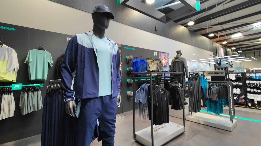 Reprimo shop-in-shop retail display showcasing mannequins dressed in athletic apparel, surrounded by neatly arranged sportswear on sleek black racks.