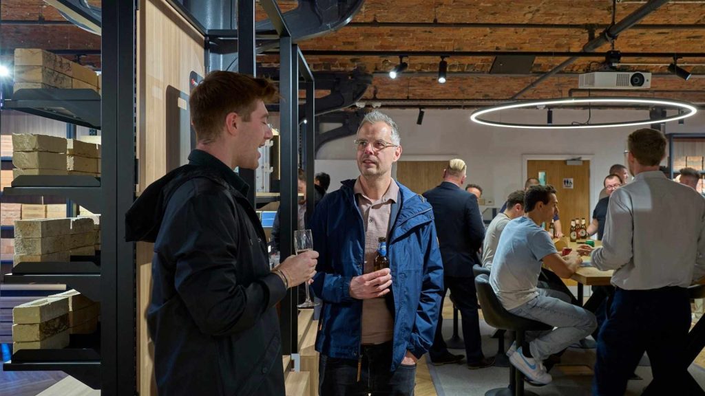 Attendees networking at the Manchester Brick Specialists showroom event, surrounded by brick samples and a modern industrial interior design