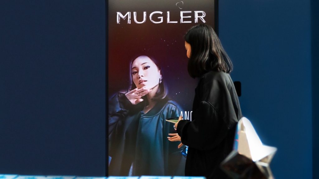 Customer interacting with a digital Mugler display showcasing branded content, creating a modern and immersive retail experience.