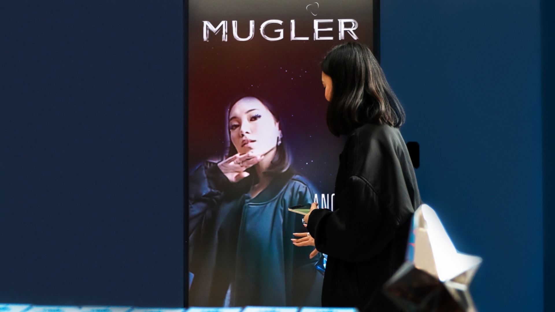 Customer interacting with a digital Mugler display showcasing branded content, creating a modern and immersive retail experience.